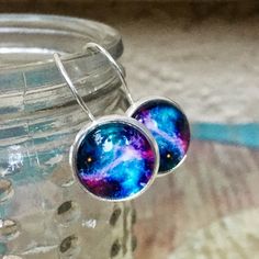 I handmade these galaxy constellation glass earrings using: -Glass cabochons measure 12mm in diameter, and are attached to handmade sealed images, which sit in 12mm sterling silver 925 settings of the lever back earrings -all materials used are Hypoallergenic and lead & nickel free -engraved '925', as they are genuine Sterling Silver Each package contains the pair(s) earrings on a black earring display card which are placed in a small chiffon drawstring pouch ('organza gift bag'), then caref Handmade Silver Cosmic Jewelry, Hypoallergenic Celestial Round Earrings, Handmade Cosmic Style Jewelry For Gifts, Handmade Cosmic Jewelry For Gifts, Cosmic Style Handmade Jewelry As A Gift, Nickel-free Adjustable Space-themed Jewelry, Space-themed Dangle Jewelry Gift, Space-themed Drop Earrings As Gift, Sterling Silver Space-themed Jewelry