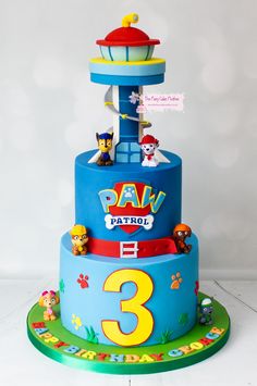 a three tiered birthday cake with cartoon characters on the top and bottom layer is blue