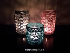 three glass jars sitting on top of a table next to each other with lit candles in them