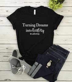 a t - shirt that says turning dreams into reality is next to jeans and shoes