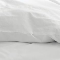 an unmade bed with white sheets and pillows