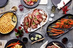 a table topped with plates filled with meat and veggies next to other foods