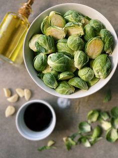 a white bowl filled with brussel sprouts next to a cup of coffee