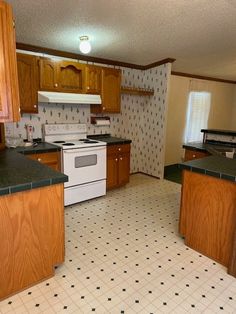 an empty kitchen with white appliances and brown cabinets