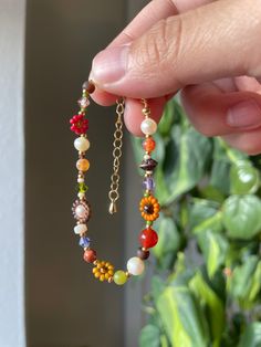 a person holding onto a beaded bracelet with beads and charms hanging from it's sides