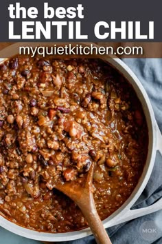 a pot filled with chili and beans on top of a wooden spoon next to a blue towel