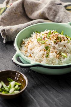 a green bowl filled with rice next to two small bowls full of other food items