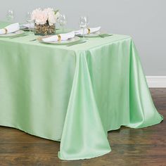 the table is set for two with place settings on it, along with wine glasses and napkins