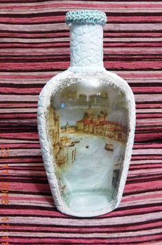 a white vase sitting on top of a striped table cloth