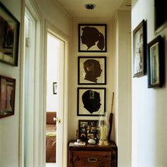 a hallway with pictures on the wall and an old dresser