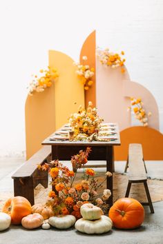 the table is set with pumpkins and flowers on it, along with other decorations