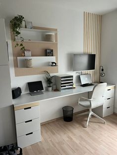 a white desk with two laptops on top of it and a plant in the corner