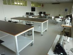 an office with desks and chairs in the middle of it, including one for computer monitors