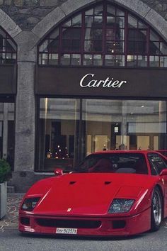 a red sports car is parked in front of a building with large windows and the name cartier on it