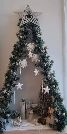 a christmas tree with white and silver stars on it's top, surrounded by other decorations