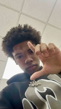 a young man making the peace sign with his hand while standing in front of a ceiling