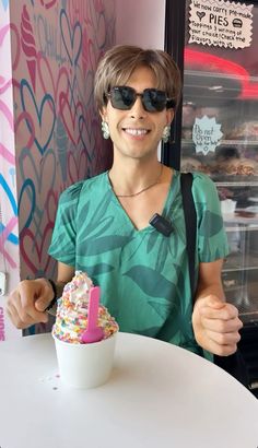 a woman sitting at a table with a cupcake in front of her and smiling