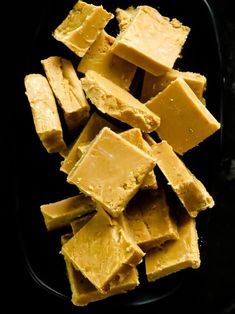 pieces of yellow fudge sitting on top of a black plate