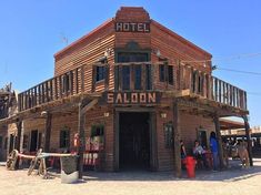 people are standing in front of a building that is made out of wood and has the name saloon on it