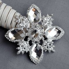 a snowflake brooch is sitting on a piece of white string and it's attached to a bracelet