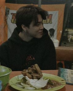 a man sitting at a table with food in front of him on a green plate