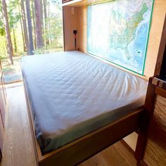 a bed with a map on the wall next to it and a window in front of it