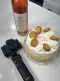 a cake with cookies on it next to a camera and a bottle of booze