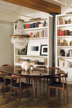 the dining room table is surrounded by chairs and bookshelves with chandelier