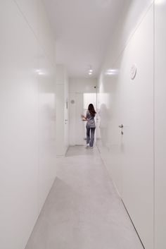 a woman is walking down the hallway in an office building with white walls and floors