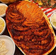 a large platter filled with lots of food on top of a wooden table next to other plates