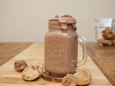 a chocolate smoothie in a mason jar on a wooden table with some walnuts around it