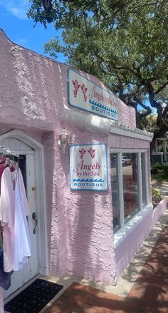 a pink store front with clothes hanging outside and trees in the backgroung