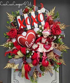 the wreath is decorated with red and white ribbons, flowers, and a love sign