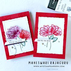 two cards with flowers on them sitting next to each other, one is red and the other is white