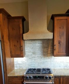 a stove top oven sitting inside of a kitchen next to wooden cupboards and cabinets