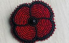 a red and black beaded brooch sitting on top of a table