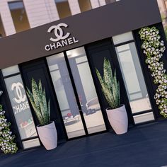 the entrance to a chanel store with two large planters