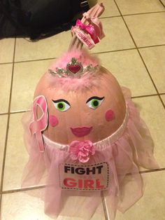 an egg with a pink ribbon and tiara on it's head sitting on a tile floor