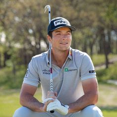 a man sitting on the ground with a golf club in his hand and wearing a hat