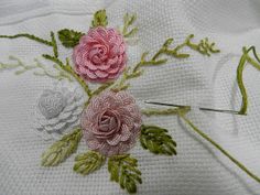 two roses are on the table with thread and needles in it, next to each other