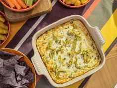 a casserole dish with broccoli and cheese in it next to bowls of vegetables