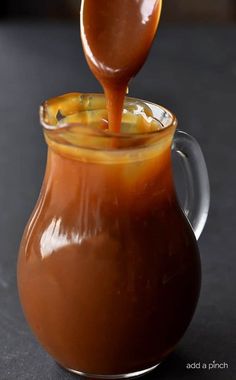 caramel sauce being poured into a glass pitcher