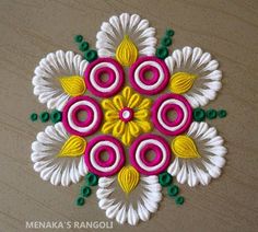 an intricately designed flower design on a wooden surface with green and yellow beads around it