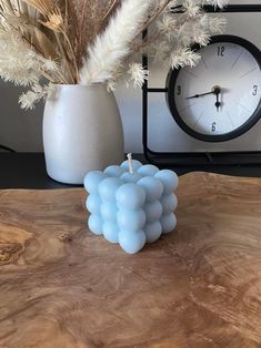 a table with a clock and vase on it, next to some dried plants in front of the clock