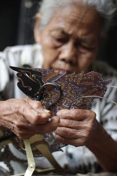 an old woman holding a butterfly in her hands