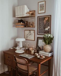 a wooden desk topped with a laptop computer next to a vase filled with tulips