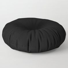 a black round pillow sitting on top of a white floor