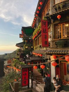 people are walking down the stairs in front of buildings with red lanterns hanging from them