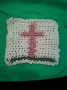 a crocheted object with a pink cross on it sitting on top of a green cloth