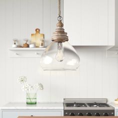 a light that is hanging from a ceiling in a kitchen next to a stove top